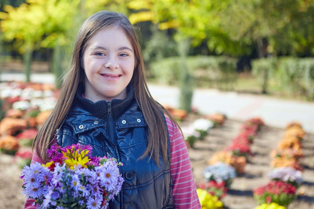 Girl with Down syndrome holding flowers in park