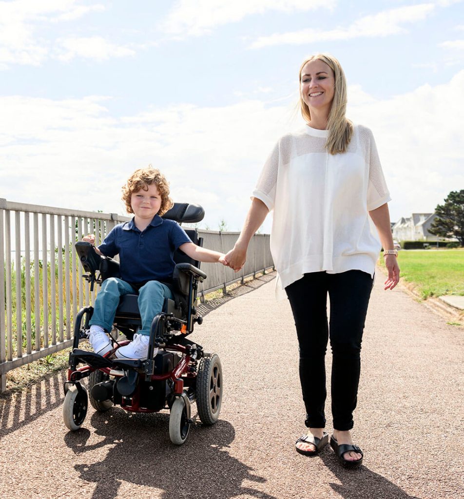Boy in wheelchair holding his mother's hand