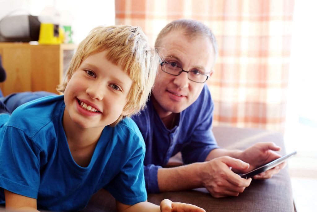 Father and son playing games on tablets.