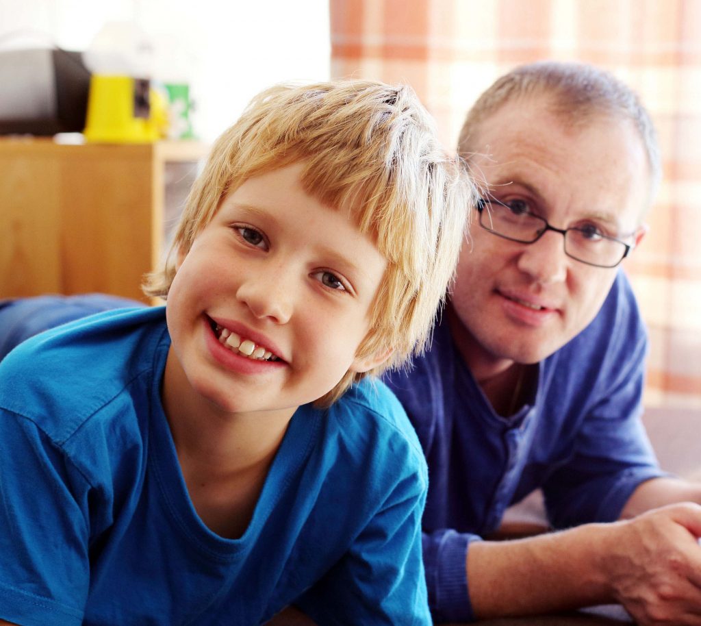 Father and son lying on the floor playing computer games.