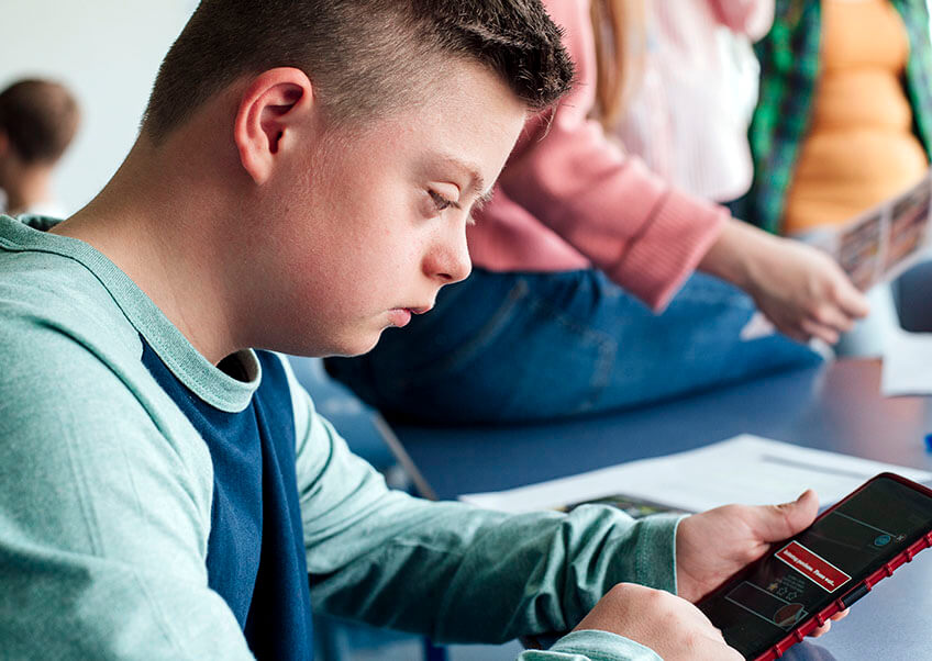 Teenage boy with Down syndrome looking at a mobile phone.
