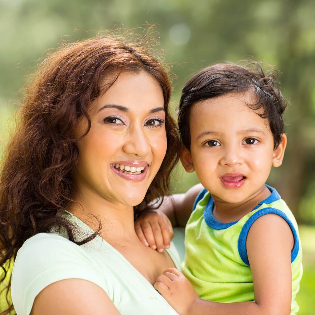 Young mother holding baby outdoors.