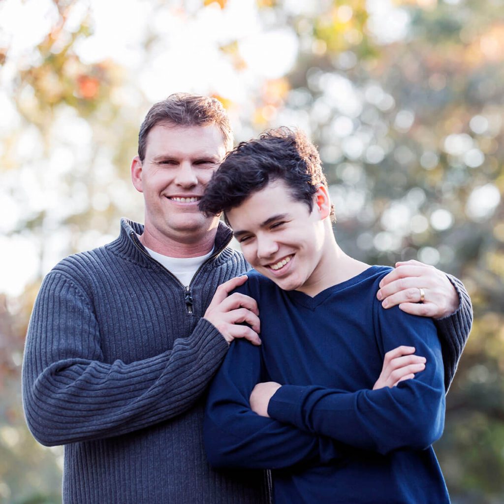 Father and teenage boy standing outdoors together.