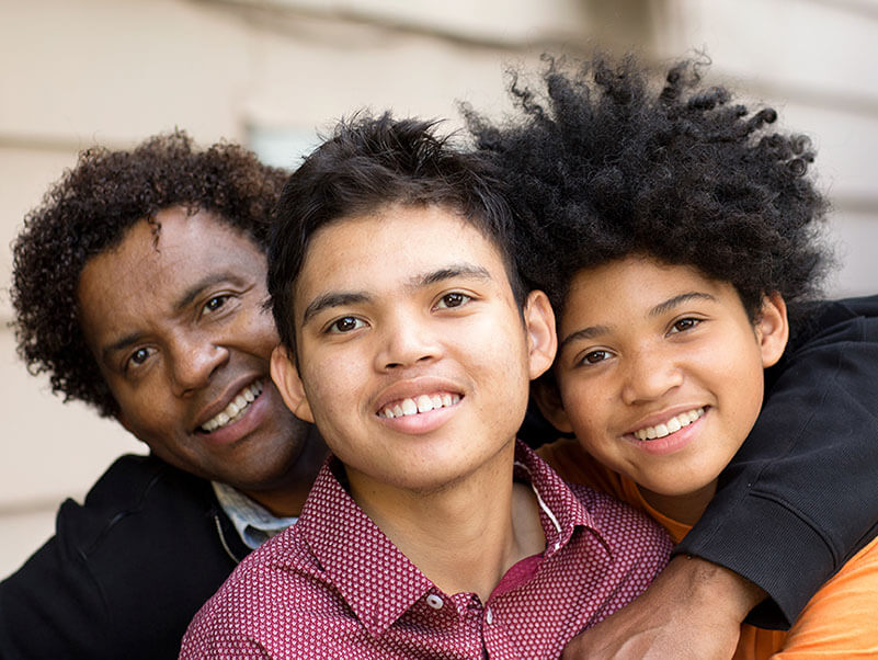 A father hugging his two sons, one of whom has autism.