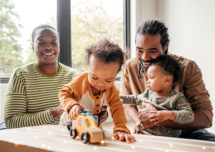 A mum and dad playing cars with their two young children.