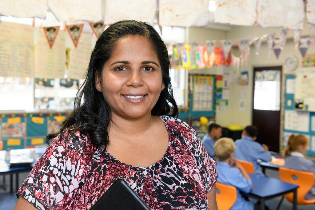 Aboriginal school teacher in the classroom smiling.