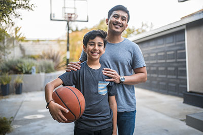 Happy boy and father standing at basketball court.