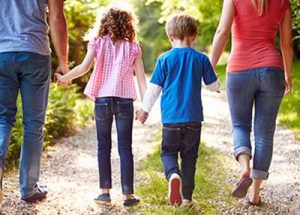 Back view of a family holding hands and walking in nature.