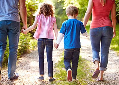 Back view of a family holding hands and walking in nature.