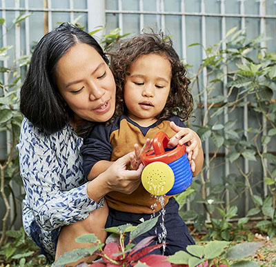 Mother and son watering plants in the backyard.