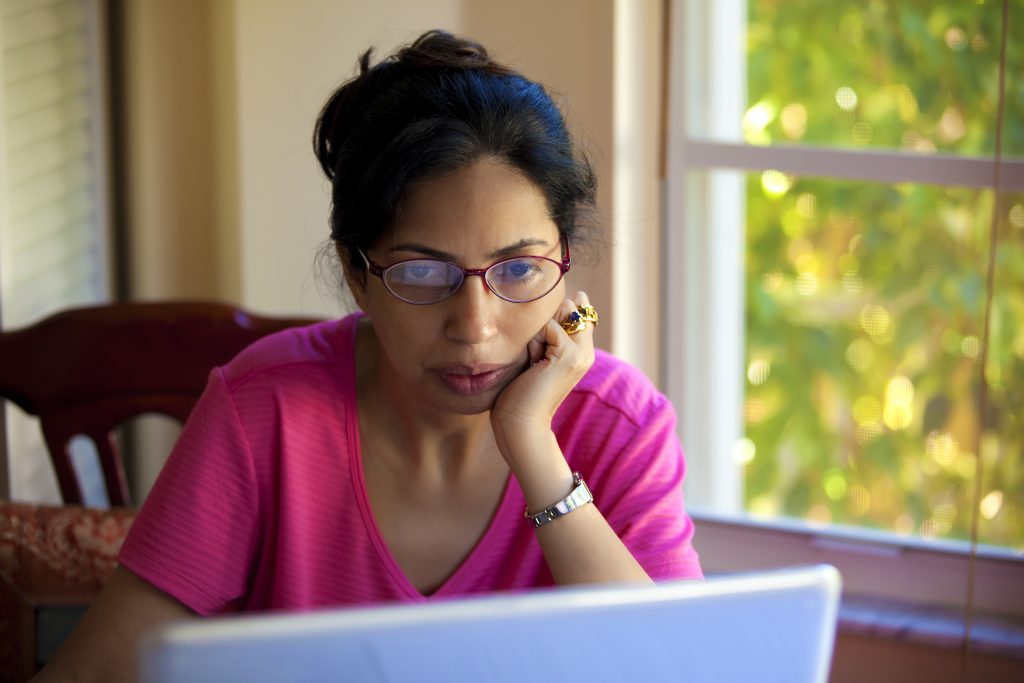 लैपटॉप पर पढ़ने में व्यस्त एक महिला।