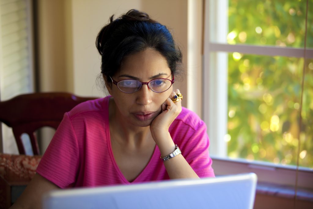 A woman busy reading on the laptop.