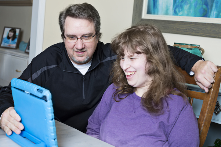 父亲通过数字平板电脑协助残疾女儿完成在线作业
