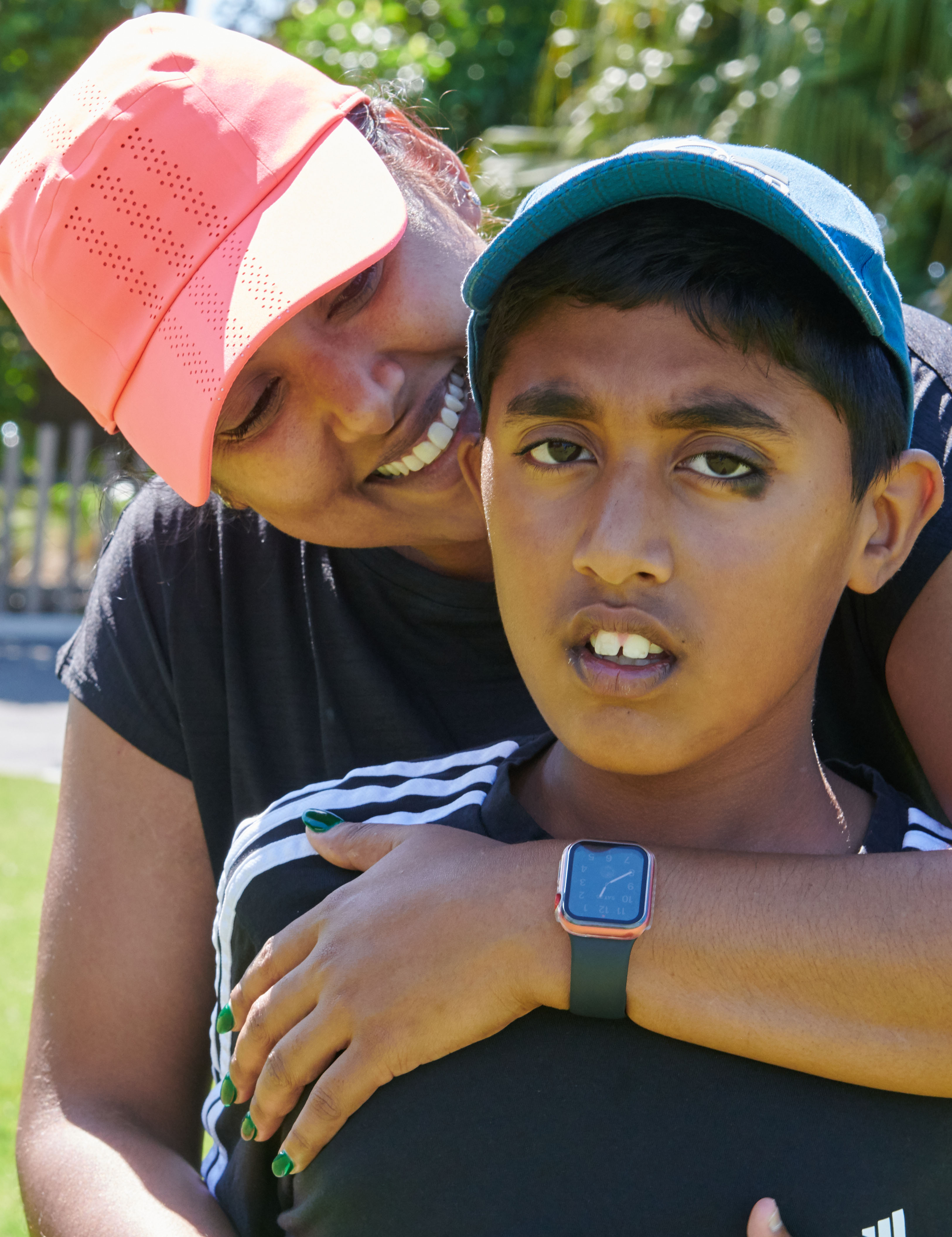 A mother with her arms wrapped around her son. The mother is smiling at her son.