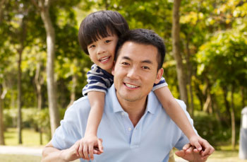 Asian father and primary school-age son enjoying outdoor activity in the park.