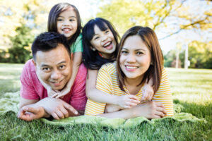 Cha mẹ châu Á đang nằm trên cỏ với hai cô con gái nhỏ trên lưng!