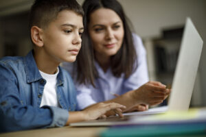 Mother and son using laptop at home