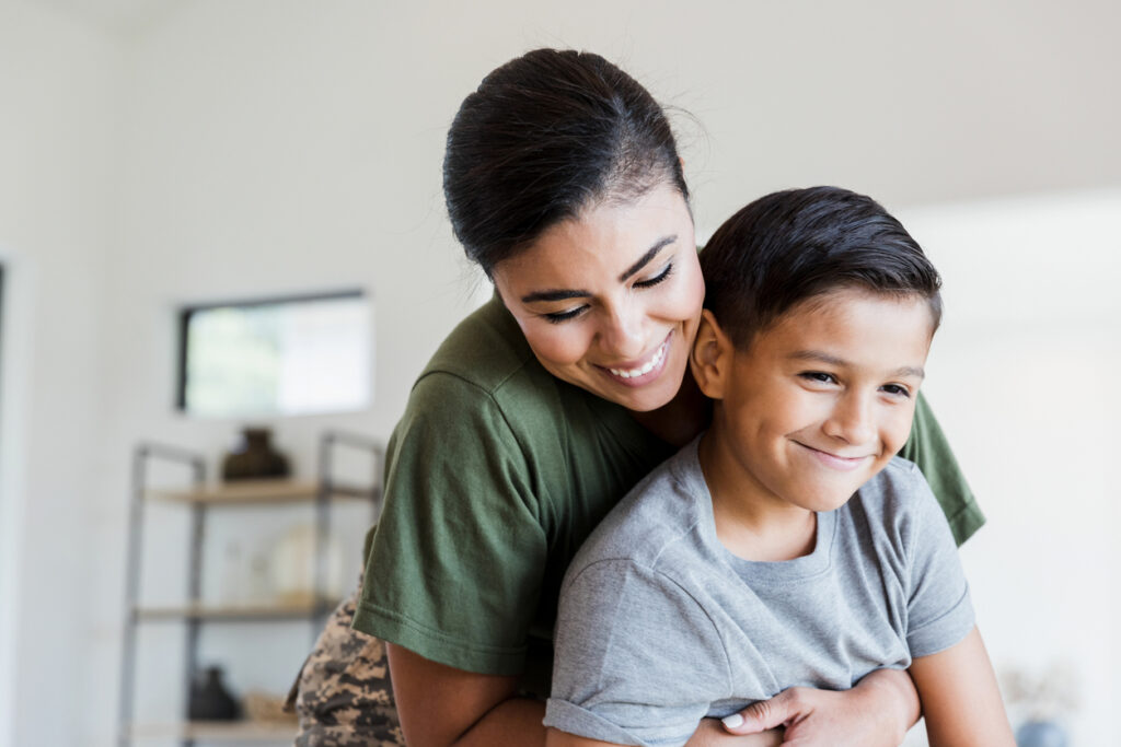 A mother hugging her son. Both are smiling.