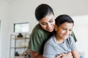 A mother hugging her son. Both the mother and child are smiling.