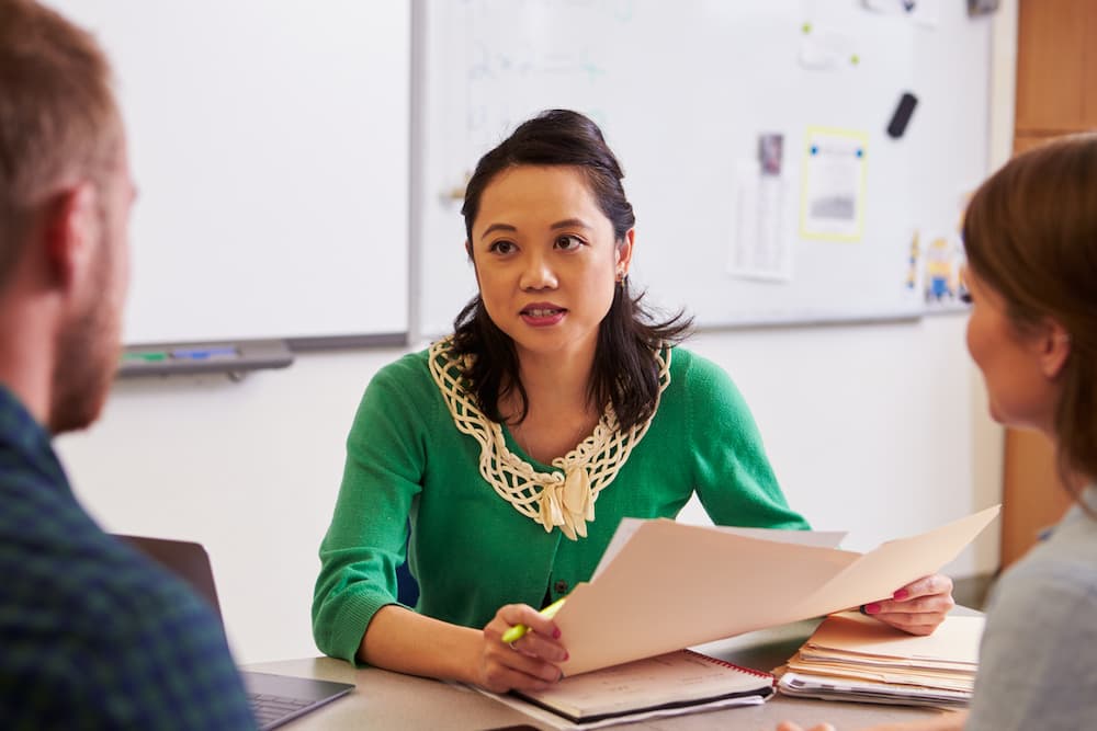 School teacher in a meeting with parents. They are sitting at a table.