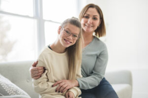 Portrait of teenage girl with disability smiling at camera with her mother