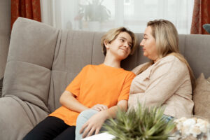 Mum and son are sitting on the couch and chatting with each other.